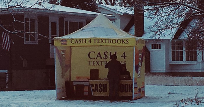 outdoor cash for textbooks station in snow with two people